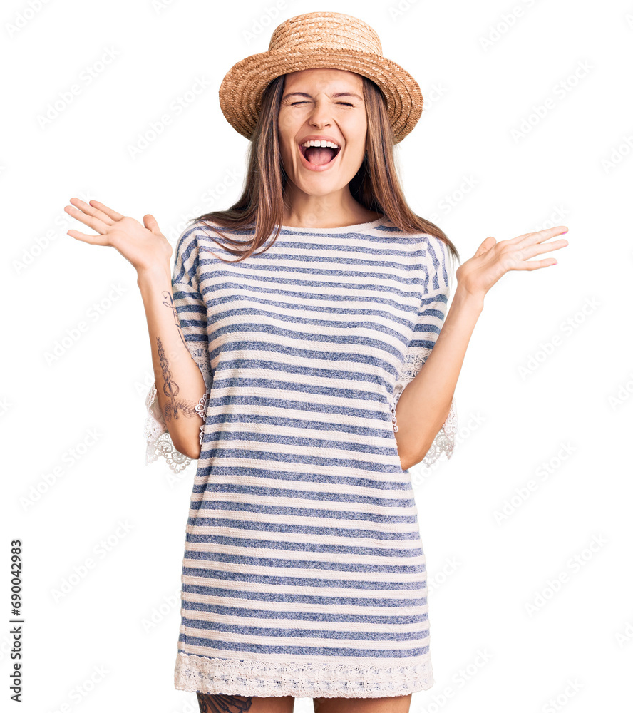 Beautiful caucasian woman wearing summer hat celebrating mad and crazy for success with arms raised and closed eyes screaming excited. winner concept Beautiful caucasian woman wearing summer hat celebrating mad and crazy for success with arms raised and closed eyes screaming excited. winner concept