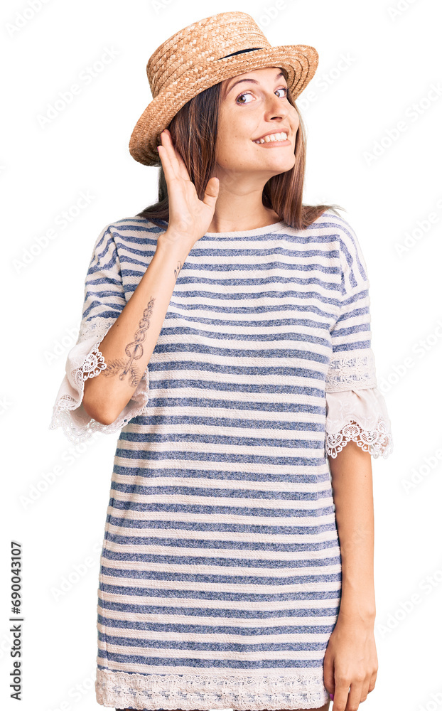Beautiful caucasian woman wearing summer hat smiling with hand over ear listening an hearing to rumor or gossip. deafness concept. Beautiful caucasian woman wearing summer hat smiling with hand over ear listening an hearing to rumor or gossip. deafness concept.