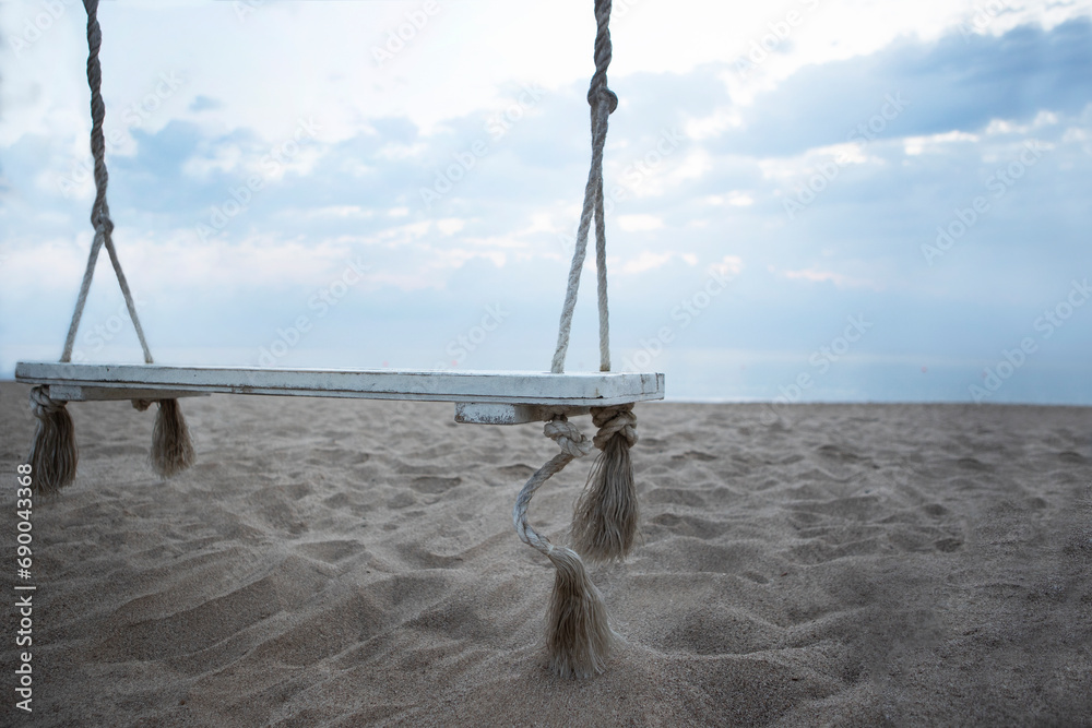 Fototapeta premium Wooden swing on the beach. The coast of the Indian Ocean. A deserted beach. The concept of summer holidays.