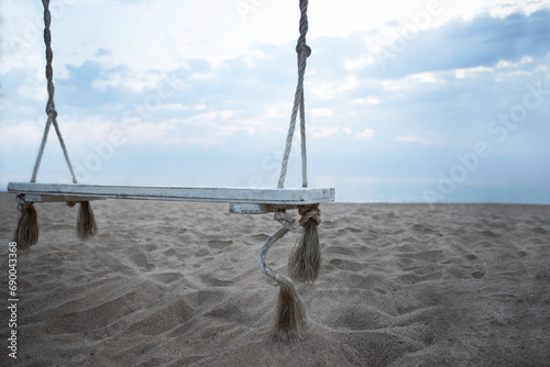 Wooden swing on the beach. The coast of the Indian Ocean. A deserted beach. The concept of summer holidays.