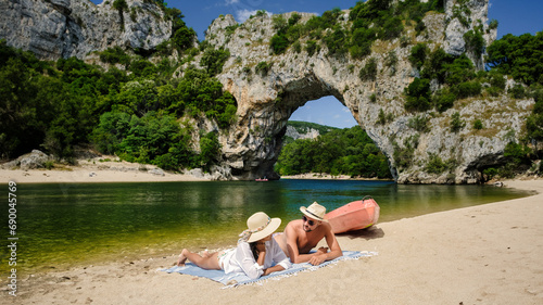 couple on vacation in the Ardeche France Pont d Arc Ardeche, view of Natural arch in Vallon Pont d'Arc in Ardeche canyon in France Europe Rhone Alps Dordogne, men and woman at the beach by the river