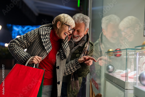 Slika na platnu Thrilled senior couple shopping for gifts standing in front of a store at shopping mall