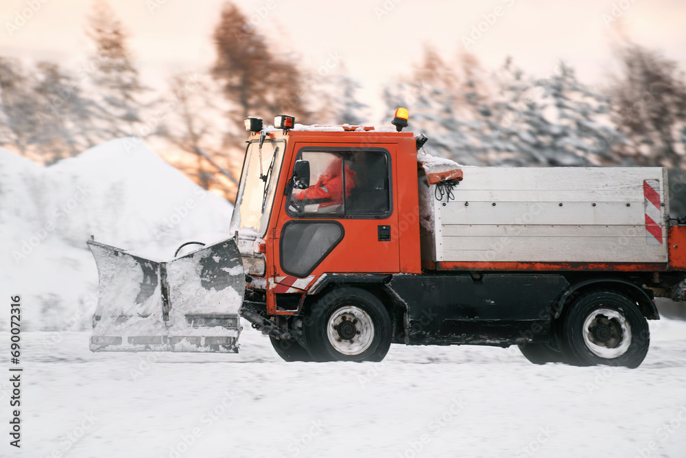 Tractor with mounted salt and sand spreader, road maintenance - winter gritter vehicle. Municipal service melting ice and snow on streets. Diffusing salt blend on public roads. Tractor with mounted salt and sand spreader, road maintenance - winter gritter vehicle. Municipal service melting ice and snow on streets. Diffusing salt blend on public roads.