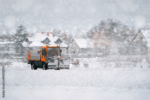 Tractor with mounted salt and sand spreader, road maintenance - winter gritter vehicle. Municipal service melting ice and snow on streets. Diffusing salt blend on public roads.