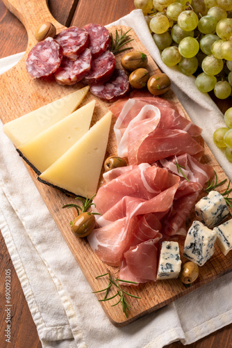 Tagliere con vari antipasti italiani: prosciutto crudo, gorgonzola, salame, pecorino e olive - cibo rustico europeo 
