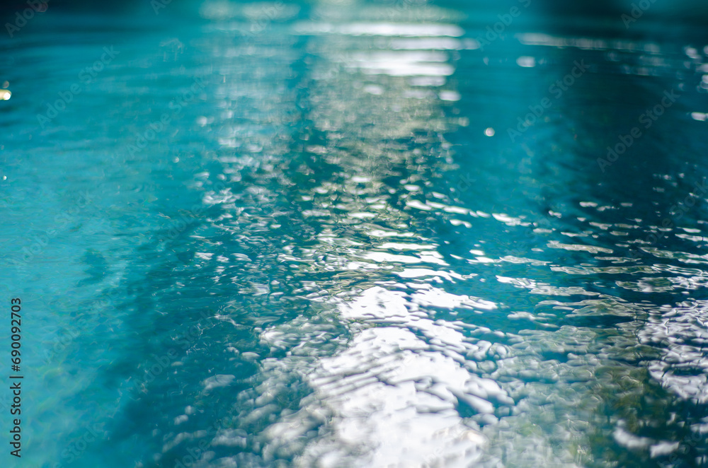 Blurred and abstract light reflected on the turquoise water of an hotel pool background