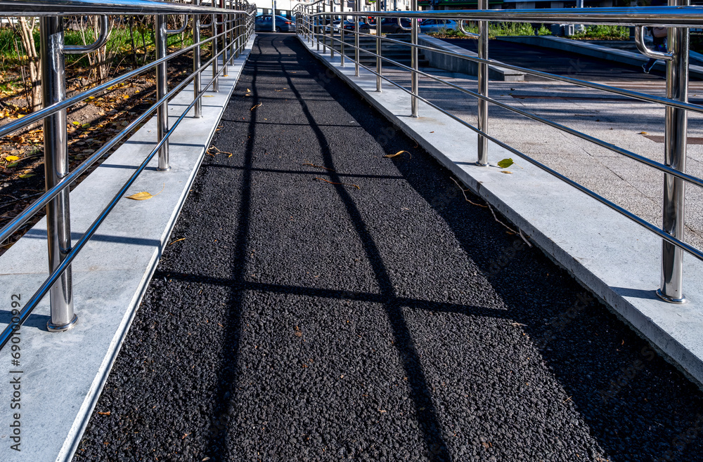 A pedestrian path made of asphalt with iron railings. A pedestrian path made of asphalt with iron railings.