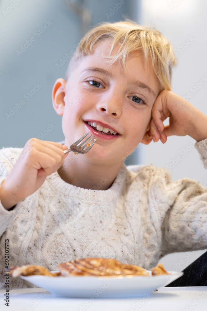 Smiling boy looking at camera while eating pancakes Smiling boy looking at camera while eating pancakes