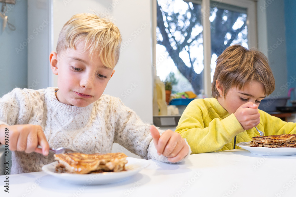 Two brothers eating pancakes together at home Two brothers eating pancakes together at home