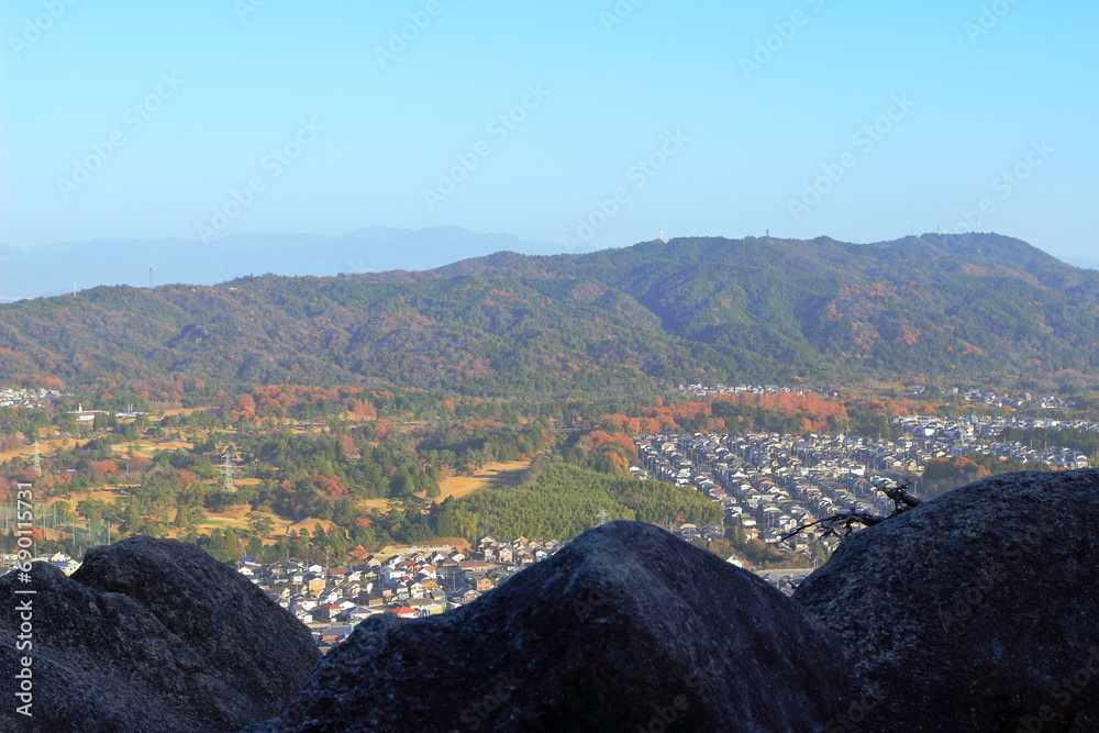 Obraz premium 滋賀県 菩提寺山の岩越しにみる湖南市と色づく山
