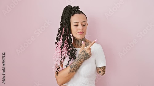 Confident hispanic amputee woman in t-shirt, standing against a rosy pink isolated background. she's pointing to the side with a serious face, showing off an advertisement. photo