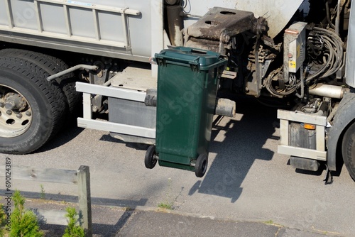 The garbage collection machine picks up trash from private green trash bins. photo
