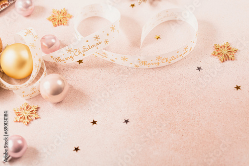 Festive Christmas and New Year background with gold and pink baubles, ribbons and stars. White ribbon with Merry Christmas written. Flat lay, top view with copy space