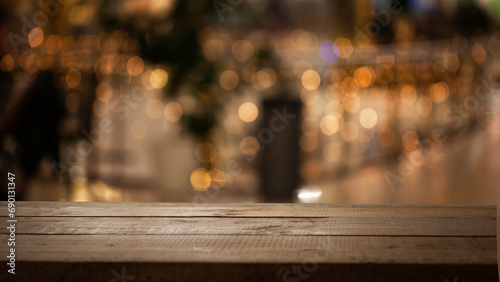 Empty wooden table top on blur light golden bokeh of cafe restaurant, bar in a dark background. photo