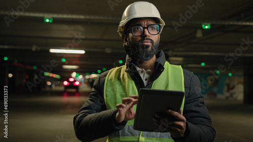 Foreman inspecting parking lot underground urban industrial heavy industry engineer Arabian man Indian builder in hard hat architect manufacture worker digital tablet talking video call conference