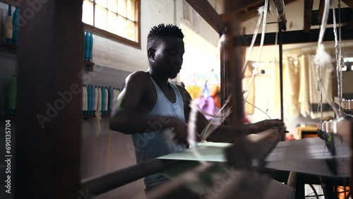 Man, loom and fabric or textiles and cotton production at clothing factory, manufacturing and craftsmanship. Black male person, warehouse and weaving thread or industry, wool and designer or skill photo