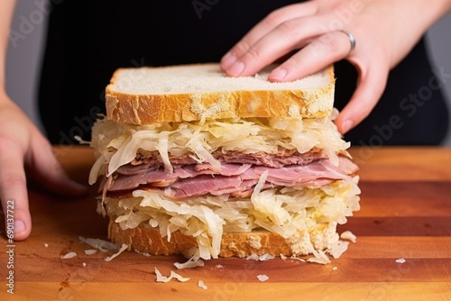 hand pressing down on a sauerkraut sandwich to flatten it