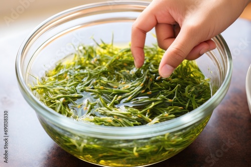 fingers tossing seaweed salad in a glass bowl photo