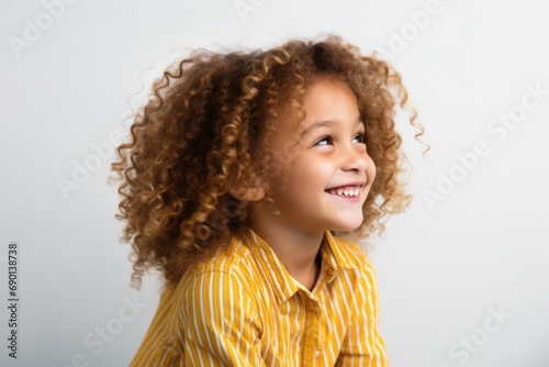 young girl with golden curls smiling while looking away from the camera