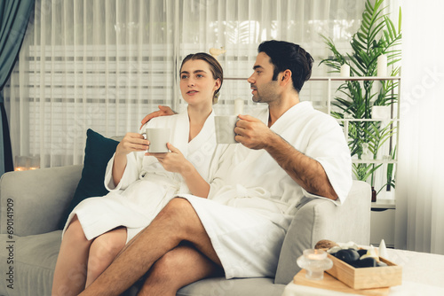 Beauty or body treatment spa salon vacation lifestyle concept with couple wearing bathrobe relaxing with drinks in luxurious hotel spa or resort room. Vacation and leisure relaxation. Quiescent