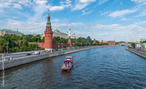 View of Kremlin with Vodovzvodnaya tower, Grand Kremlin Palace from repaired Bolshoy Kamenny Bridge in Moscow city on sunny summer day. Cruise ship sails on the Moscow river photo