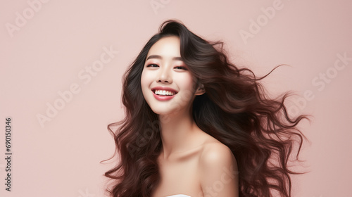 Fashion beauty portrait of young asian model with waving dark hair on beige background.