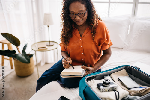 фотографія Mature traveler ticking off her packing list at home