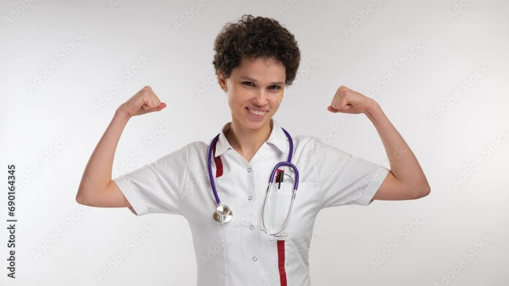 young curly female doctor showing strong hands muscle young curly female doctor showing strong hands muscle