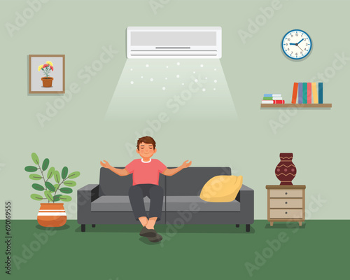 Young man sitting on sofa relaxing enjoying under air cooling with Air Conditioner at home
