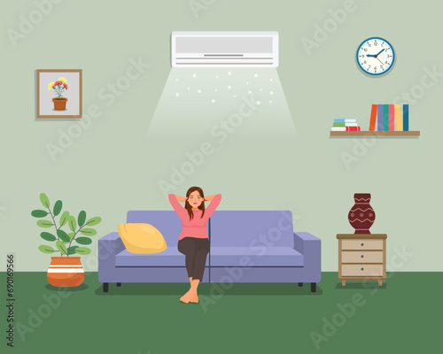 Young woman sitting on sofa relaxing enjoying under air cooling with Air Conditioner at home