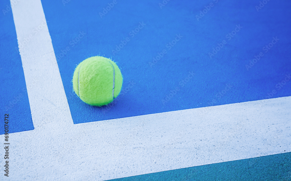 Tennis ball on a blue paddle tennis court.