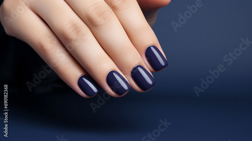 Glamour woman hand with navy blue nail polish on her fingernails. Navy nail manicure with gel polish at luxury beauty salon. Nail art and design. Female hand model. French manicure.