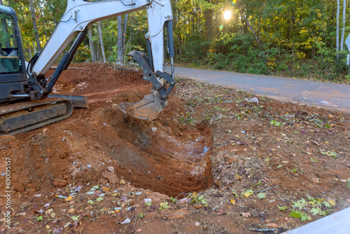 Worker uses a tractor to excavate ditch for laying drainage conduit