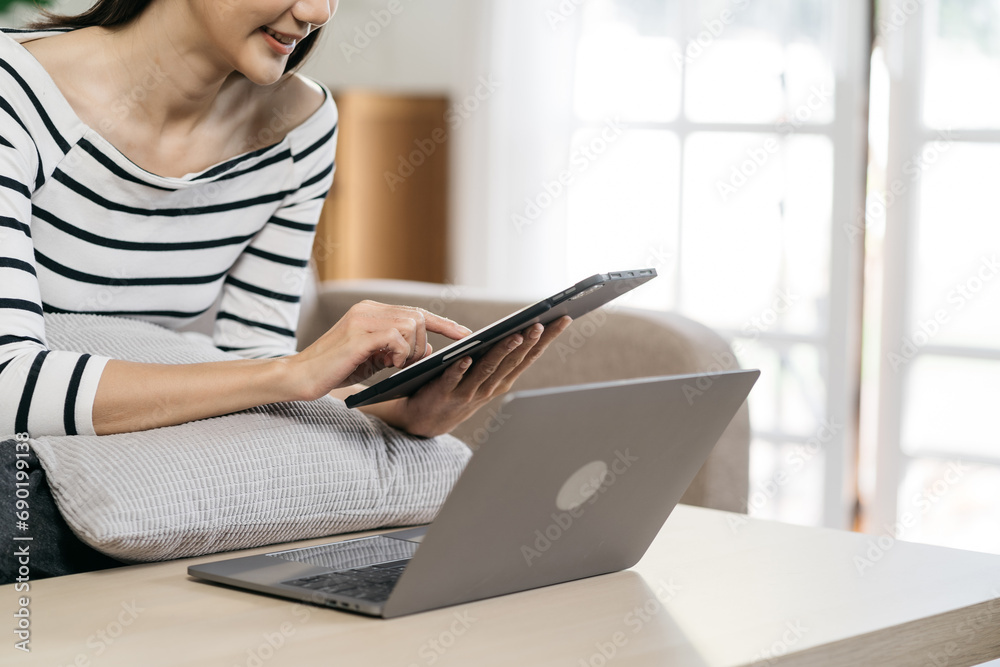 Women are using a mobile phone and laptop wifi connection sitting on sofa, home office workplace lifestyle people. Women are using a mobile phone and laptop wifi connection sitting on sofa, home office workplace lifestyle people.