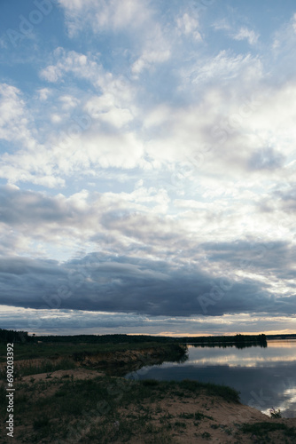 cloudy sky at sunset on the sandy shore of the lake © sadreevaa