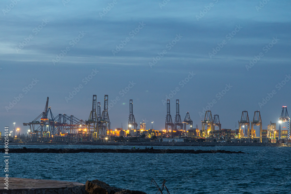 Cranes with beautiful lighting in the port on the blue sea in the evening