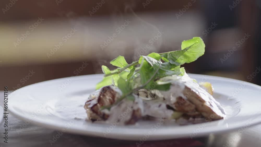 Grilled beef steak with cream sauce and vegetables served on plate with hot steam, cinematic isolated slow motion shot Grilled beef steak with cream sauce and vegetables served on plate with hot steam, cinematic isolated slow motion shot