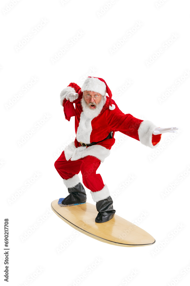 Senior man, Santa Claus with bag filled with presents surfing on board isolated on transparent background. Concept of winter holidays, Christmas and New Year, celebration, merry time Senior man, Santa Claus with bag filled with presents surfing on board isolated on transparent background. Concept of winter holidays, Christmas and New Year, celebration, merry time