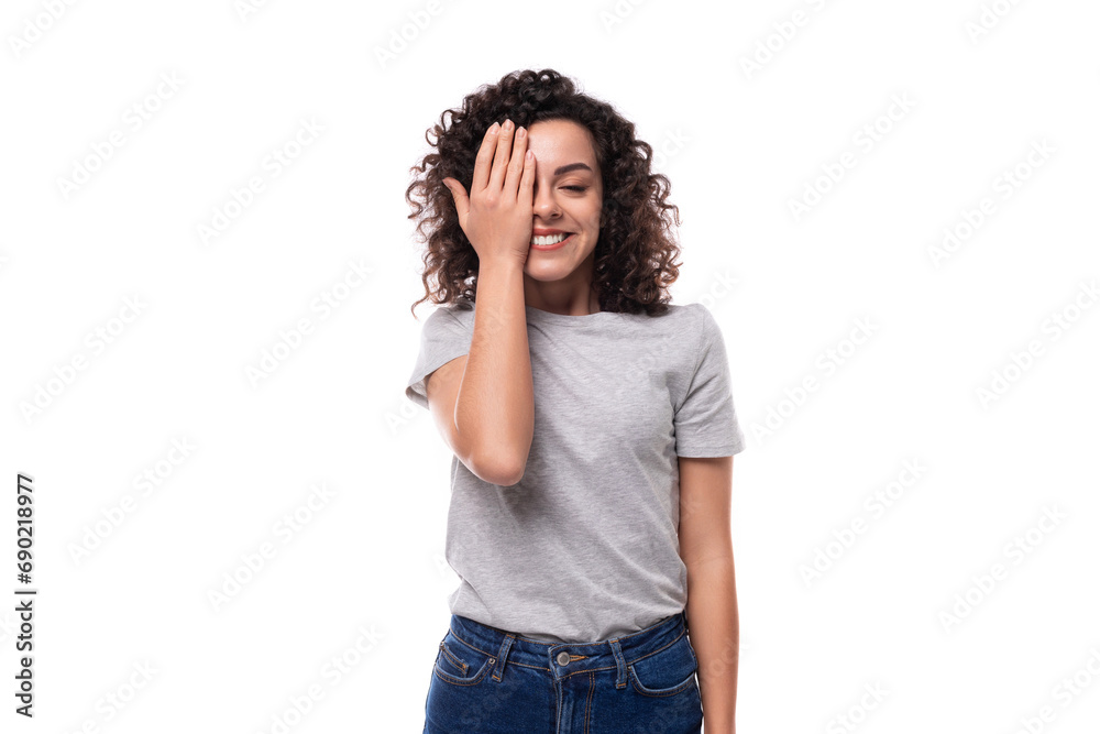 positive confident bright young european slim brunette woman with curly hair style dressed in a gray t-shirt on a white background with copy space positive confident bright young european slim brunette woman with curly hair style dressed in a gray t-shirt on a white background with copy space