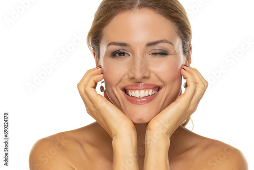 A portrait of a joyful woman with a beautiful smile and tasteful makeup,posing and winking on white background, expressing happiness and confidence