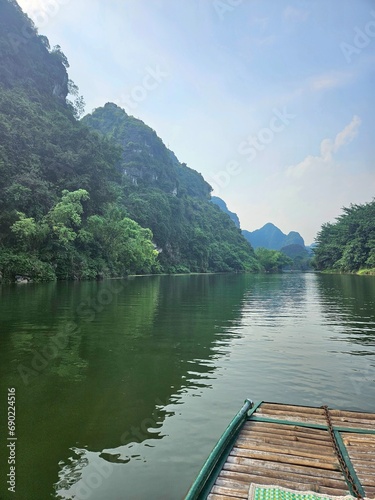 Fototapeta Naklejka Na Ścianę i Meble -  River Along Green Mountains: Boat and Breathtaking Landscape