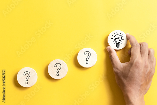 Hand holding wooden block with light bulb icon and questions mark for for creative thinking idea and problem solving concept.