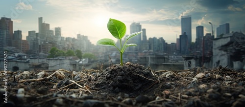Green plant growing on dry cracked earth surrounded by waste of plastic bottle and polluted city and industry on background Co2 Climate change and Plastic is impact to mother earth concept photo