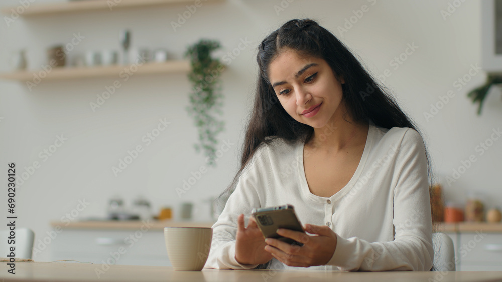 Millennial smartphone user arabian woman typing message in domestic kitchen female homeowner girl using cellphone online app make order food delivery service on mobile phone browsing cooking website Millennial smartphone user arabian woman typing message in domestic kitchen female homeowner girl using cellphone online app make order food delivery service on mobile phone browsing cooking website
