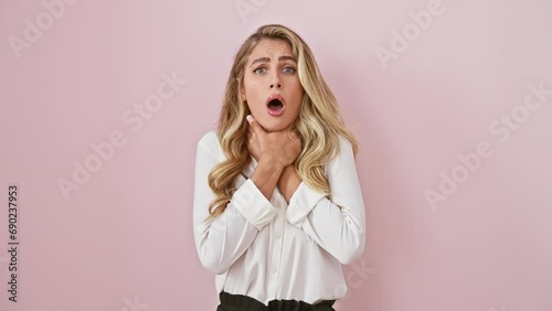 Strangled agony, young blonde woman in shirt suffers asphyxiation, a painful health problem, standing isolated over pink background