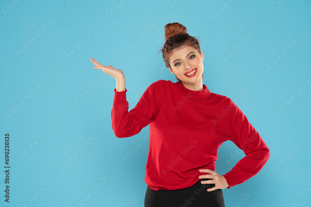 Young happy redhead woman feeling happiness and holding Empty on her palm, or advertising isolated on blue background Young happy redhead woman feeling happiness and holding Empty on her palm, or advertising isolated on blue background