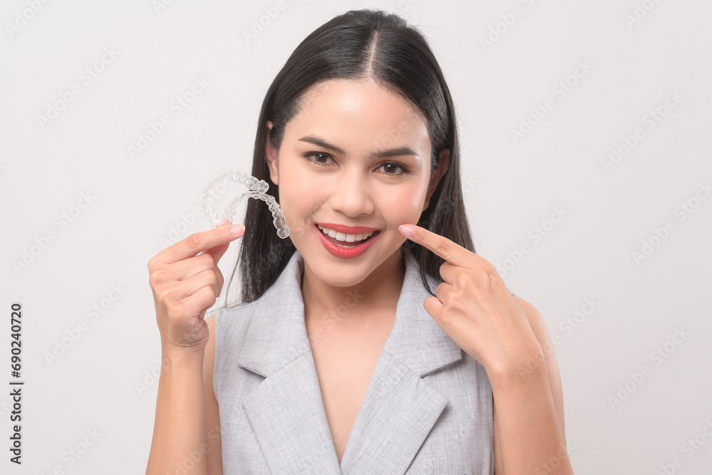 Young smiling woman holding invisalign braces in studio, dental healthcare and Orthodontic concept. Young smiling woman holding invisalign braces in studio, dental healthcare and Orthodontic concept.