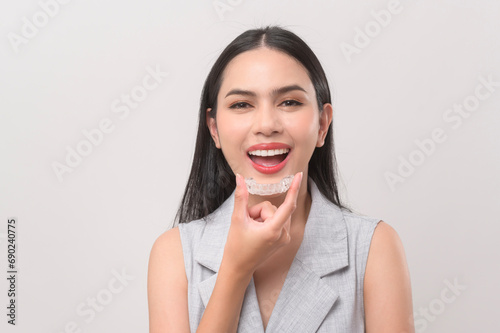 Young smiling woman holding invisalign braces in studio, dental healthcare and Orthodontic concept.