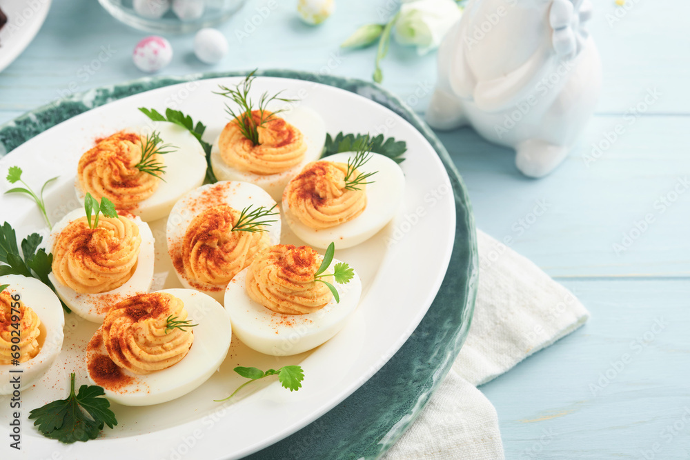 Stuffed or deviled eggs with paprika and parsley on blue plate for easter table. Traditional dish for Easter. Healthy diet food for breakfast. Top view, flat lay.