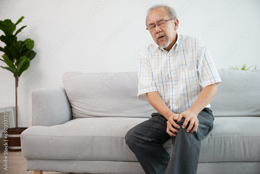 senior man suffering from knee ache on sofa senior man suffering from knee ache on sofa